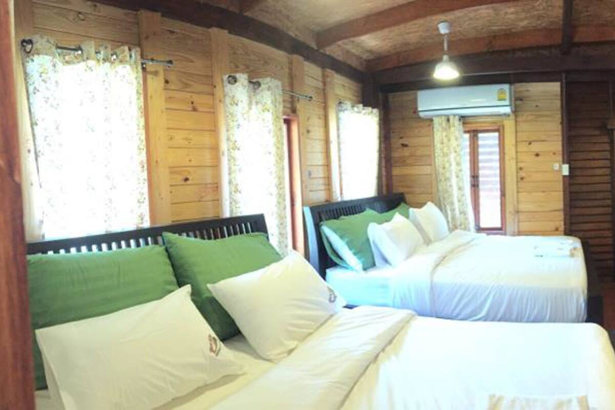 A cabin-style room with two beds, a television, and an air conditioning unit.