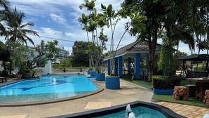 A swimming pool with a fountain feature, surrounded by palm trees and a covered seating area. - Blue Garden Resort Pattaya (Pattaya)