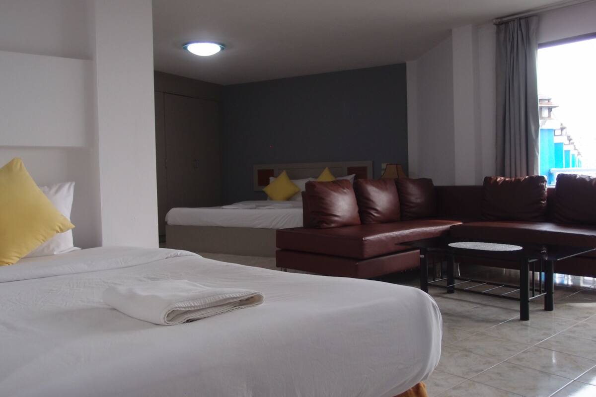 A hotel room with a bed, a sofa, a small table, and a window with curtains.