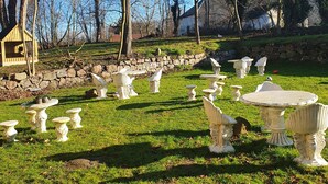 A garden with various outdoor furniture pieces, a stone wall, and leafless trees.