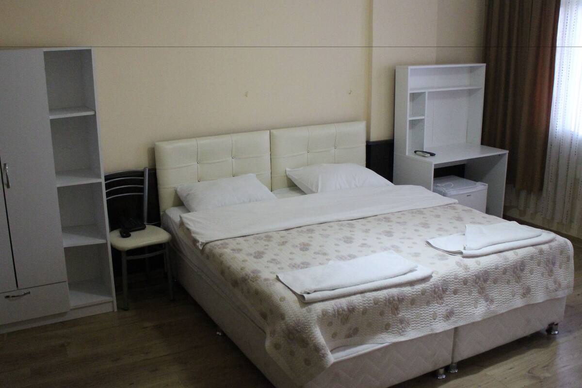 A bedroom with a bed, a chair, a wardrobe, and a small desk.