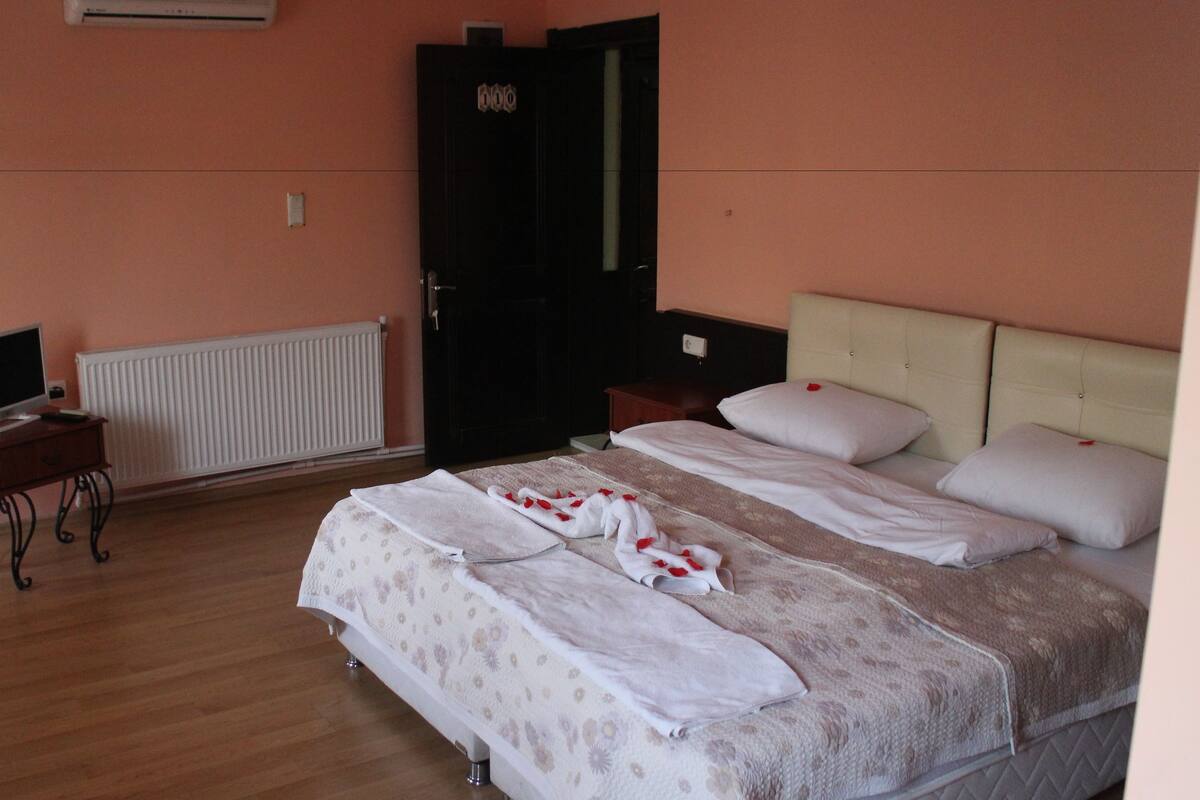 A hotel room with a bed, a desk with a computer, and a radiator.