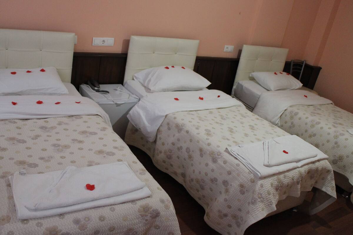 A hotel room with three beds, each with a floral-patterned bedspread and white linens.