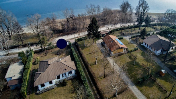 An aerial view of a residential area with houses, a large body of water, and a clear sky. - Ritratto sul Lago (Dormelletto)