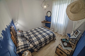 A bedroom with a bed, bedside table, lamp, and a hanging basket. - Ritratto sul Lago (Dormelletto)