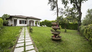 A house with a paved pathway leading to a seating area with white chairs. - Ritratto sul Lago (Dormelletto)