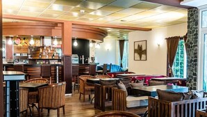 A restaurant with wooden furniture, a bar area, and a stone accent wall. - Chateau Hotel (Bansko)