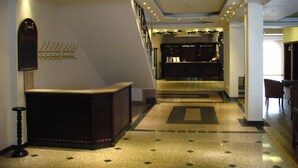 A hotel reception area with a reception desk, coat hooks, and a staircase leading to another floor. - Chateau Hotel (Bansko)
