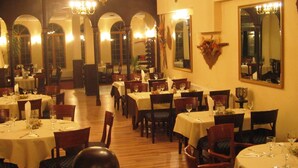 A restaurant with multiple tables, chairs, and a chandelier. - Chateau Hotel (Bansko)