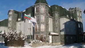 A large, multi-story building with a stone facade and a green roof. - Chateau Hotel (Bansko)