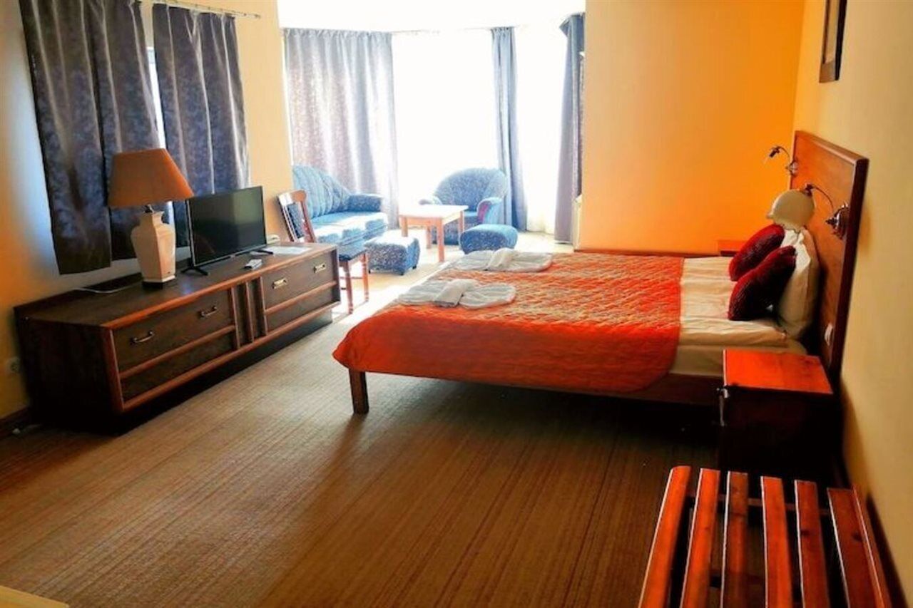 A hotel room with a bed, a TV, a dresser, and a chair.