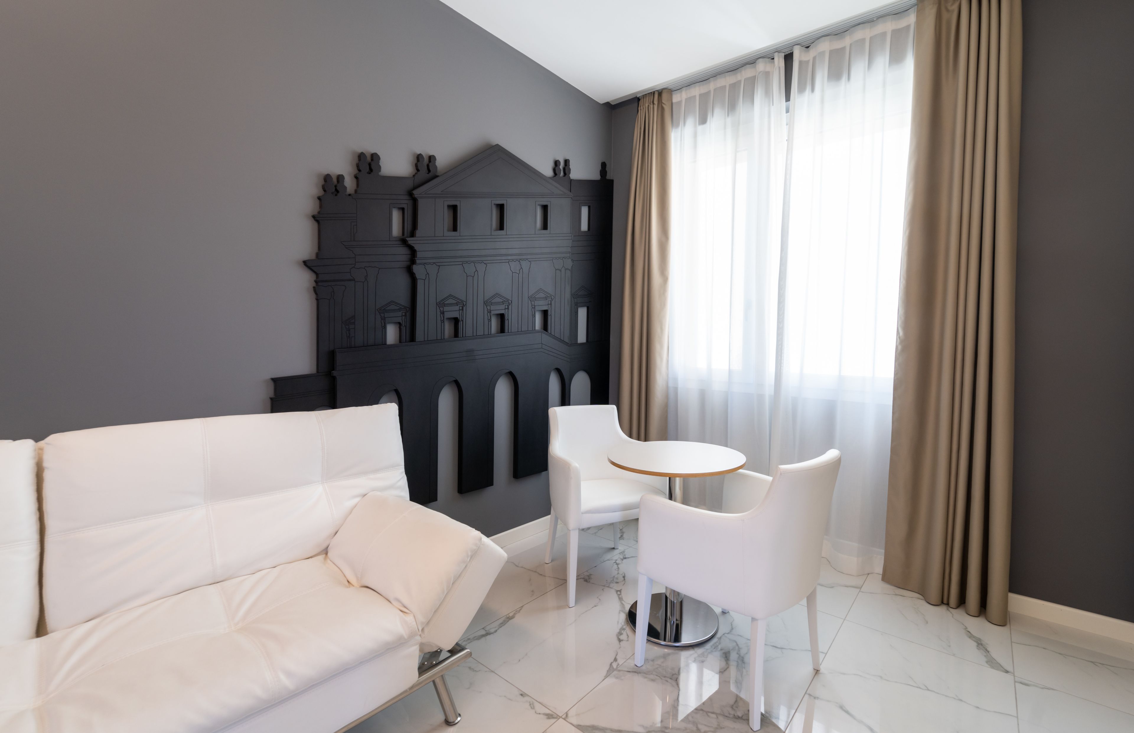 Una sala de estar moderna con un sofá blanco, una mesa redonda y un adorno en la pared.