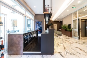 Een moderne hotellobby met een marmeren vloer, een receptiebalie, een trap en een groot raam met uitzicht op buiten.