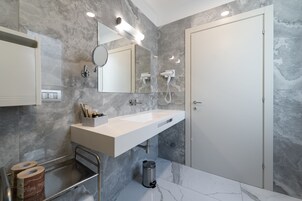 Een moderne badkamer met een grote spiegel, een witte wastafel en een handdoekrek.