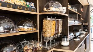 A buffet area with various food items, including cakes, pastries, and a granola bar dispenser. - Hotel Milano Castello (Milan)