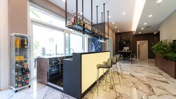 A modern bar area with a marble floor, a glass display case with bottles, and a seating area with bar stools.