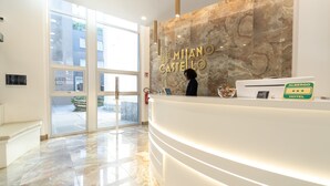 A hotel reception area with a marble reception desk, a large window, and a view of the outside. - Hotel Milano Castello (Milan)