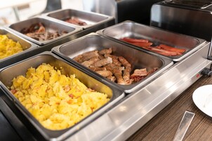Een buffet met diverse gerechten, waaronder aardappelen, worst en spek.