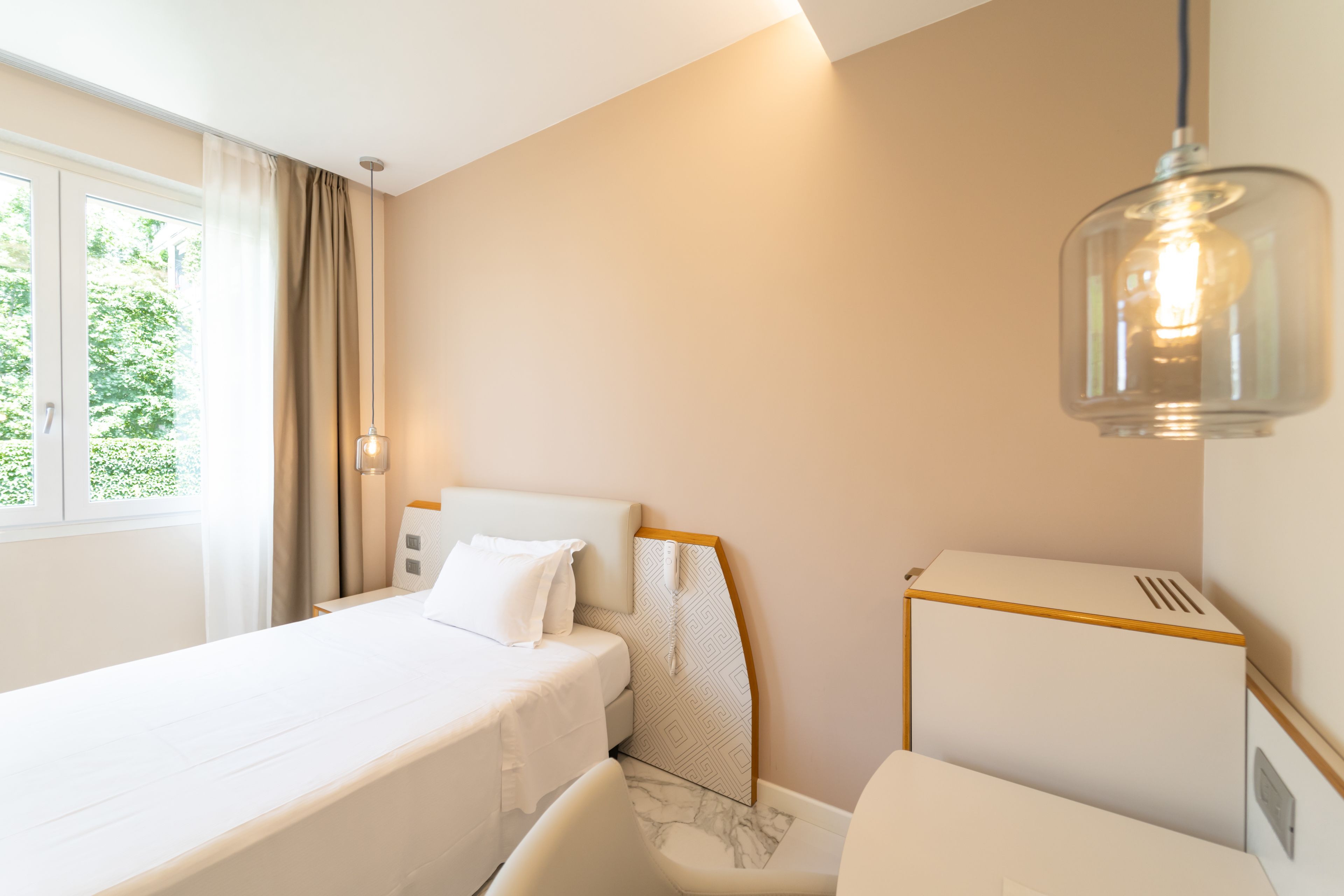 Una habitación de hotel con cama, una silla, escritorio y ventana con cortinas.
