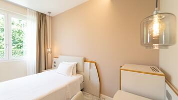 Una habitación de hotel con cama, una silla, escritorio y ventana con cortinas.