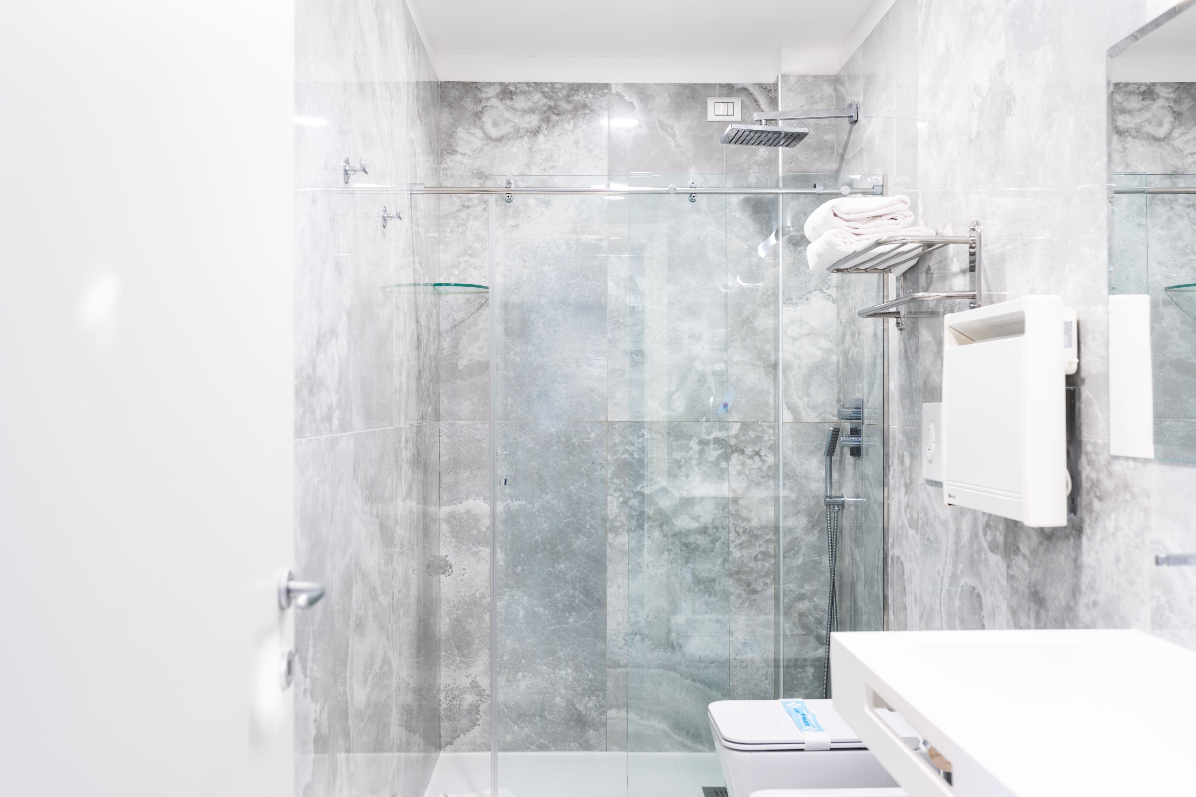 Une salle de bain moderne avec une douche à parois de verre, un lavabo blanc et un porte-serviettes.