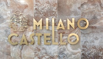 A marble wall with the text "Milan Castello" in gold letters and a decorative emblem.