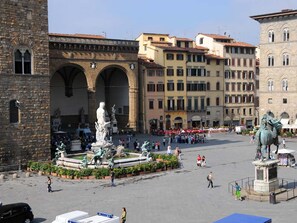 A public square with a central fountain, surrounded by historic buildings with arches and statues. - Apartment Via Fiume 1 (Florence)