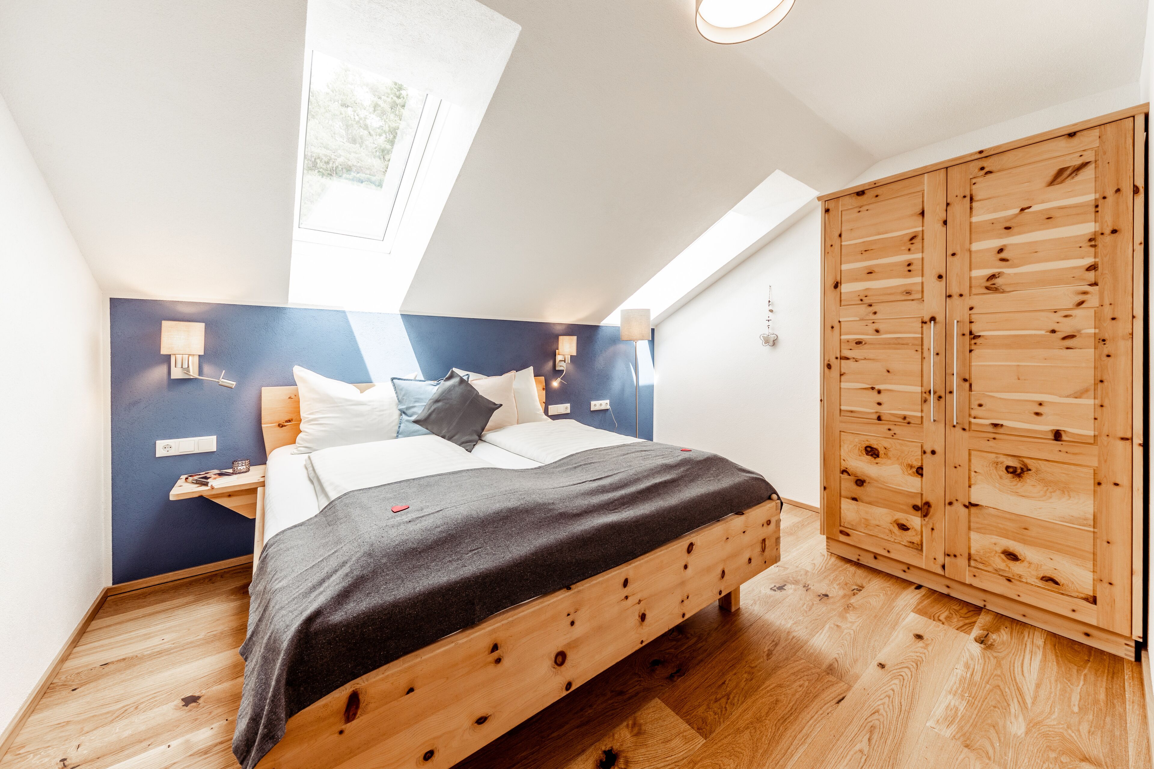 A bedroom with a wooden bed, a wardrobe, and a skylight.
