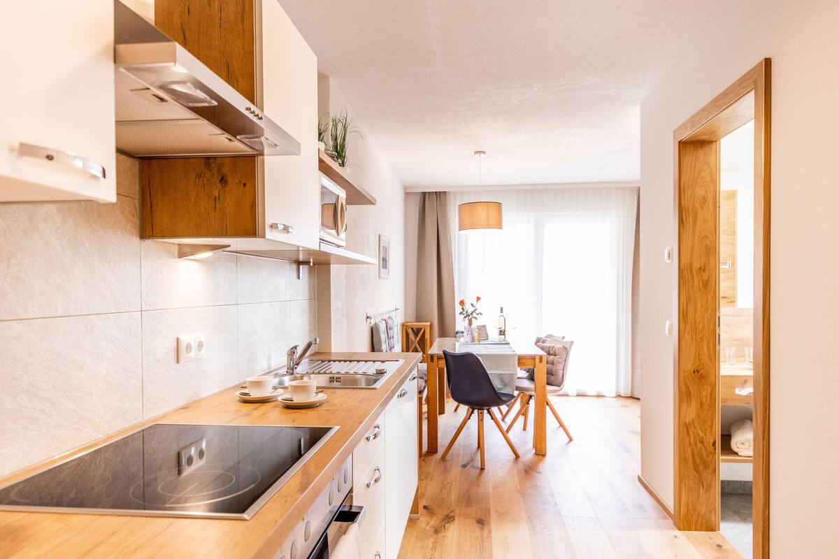 Une cuisine moderne dot ée d’une cuisinière intégrée, de meubles en bois et d’un coin repas avec une table et des chaises.