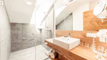 A modern bathroom with a glass shower enclosure, a wooden vanity with a sink, and a mirror.
