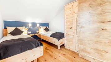 Un dormitorio con dos camas de madera, un armario y una mesita de noche con lámpara.