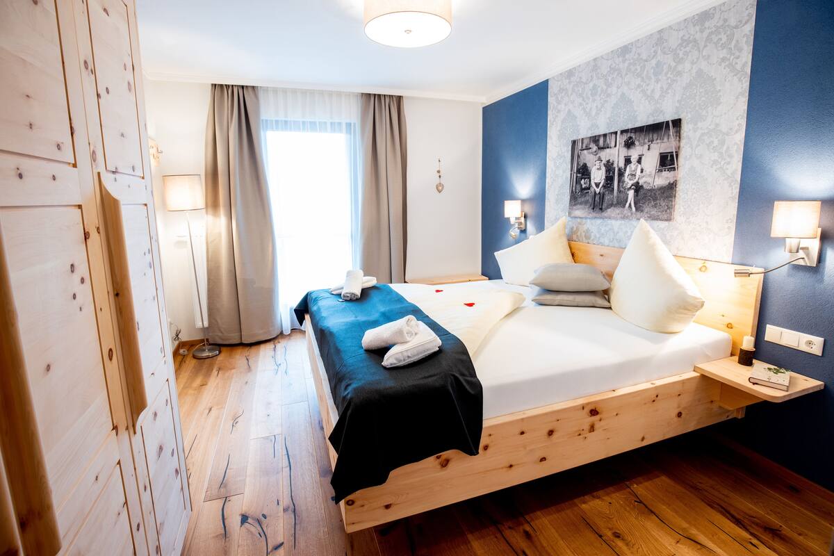 Un lit en bois avec une couvre-lit noire, des oreillers blancs et une petite table de chevet avec une lampe.