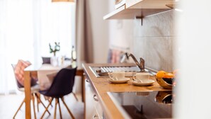 A modern kitchen with a wooden countertop, a sink, and a dining area with a chair and table. - Kärnten Apartment Turnersee (Sankt Kanzian am Klopeiner See)