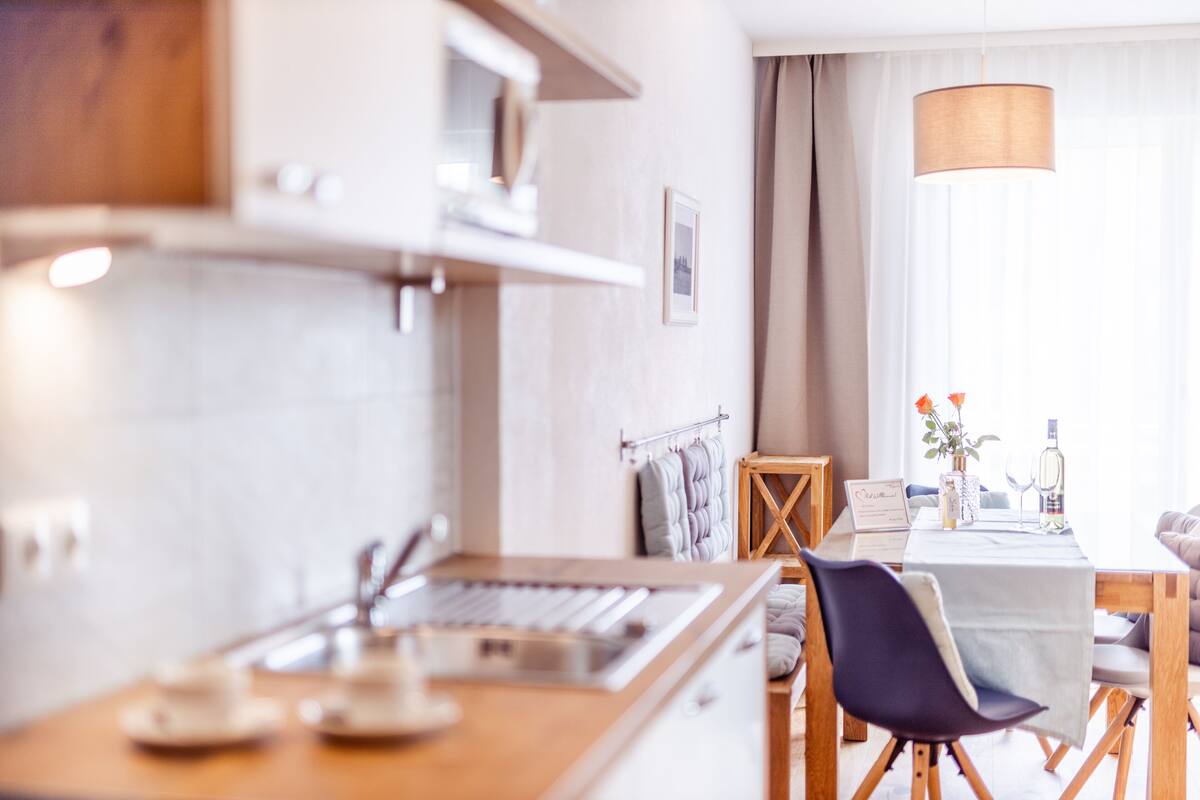 Une cuisine moderne dotée d’un plan de travail en bois, d’un évier encastré et d’un coin repas avec une table mise pour deux personnes.