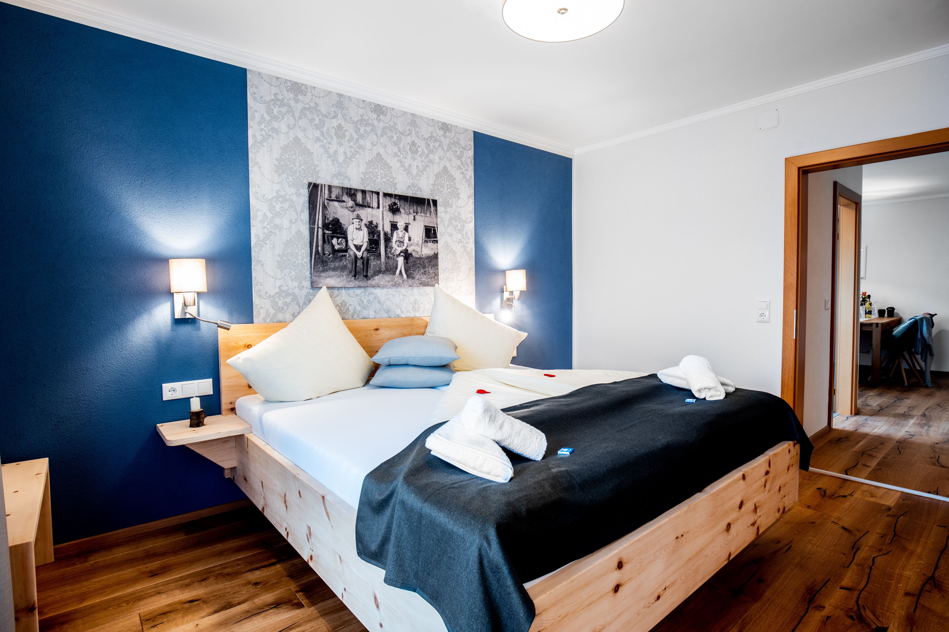 Una habitación de hotel moderna con una cama de madera, paredes azules y una foto enmarcada en la pared.