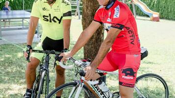 Two cyclists sitting on bicycles under a tree in a park.