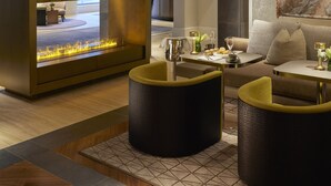 A modern lounge area with a fireplace, seating, and a dining setup. - Mandarin Oriental Savoy, Zurich (Zürich)