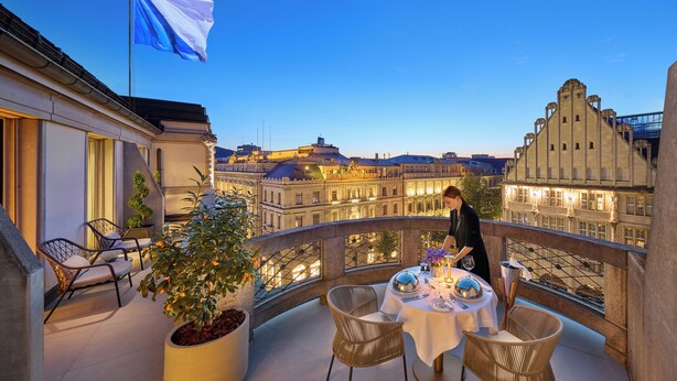 A balcony with a table set for dining, overlooking a cityscape with historic buildings. - Mandarin Oriental Savoy, Zurich (Zürich)