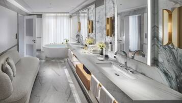 A modern bathroom with a large bathtub, a long vanity with a marble countertop, and a large mirror.