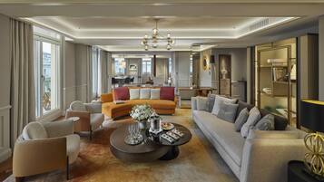 A spacious living room with a large sofa, armchairs, a coffee table, and a dining area in the background.