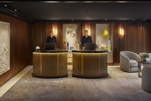 A reception area with two receptionists at desks, a round table, and a sofa.