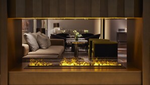 A modern living room with a glass-top fireplace, a sofa, a coffee table, and a dining area in the background. - Mandarin Oriental Savoy, Zurich (Zürich)