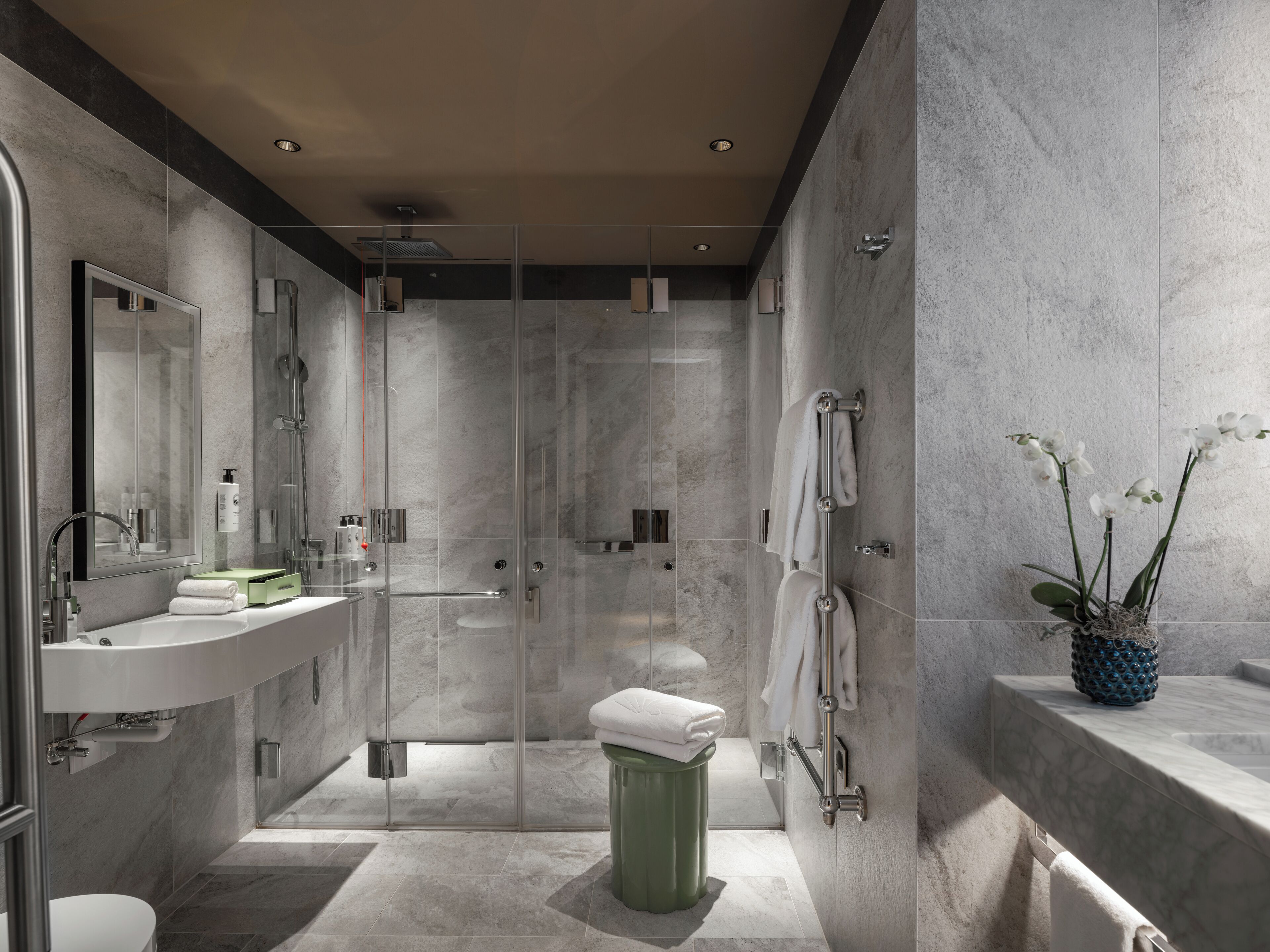 A modern bathroom with a glass-enclosed shower, a vanity with a sink, and a toilet.