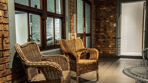 Wicker chairs near a window with a brick wall and a door. - Yalla Yalla Boutique Hotel (Emalahleni)
