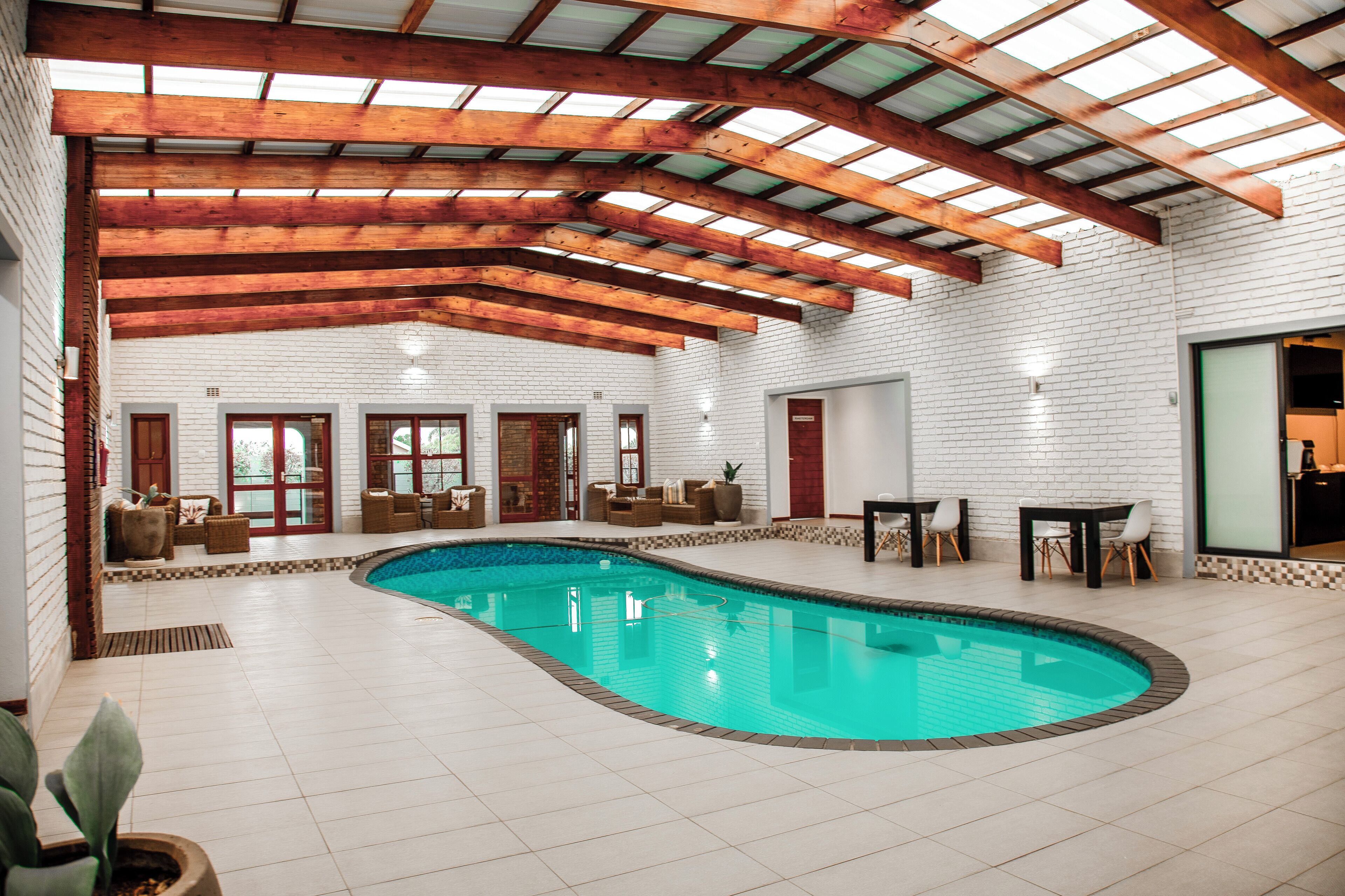 Ein Hallenbad mit Holzbalkendecke und weißen Backsteinwänden.