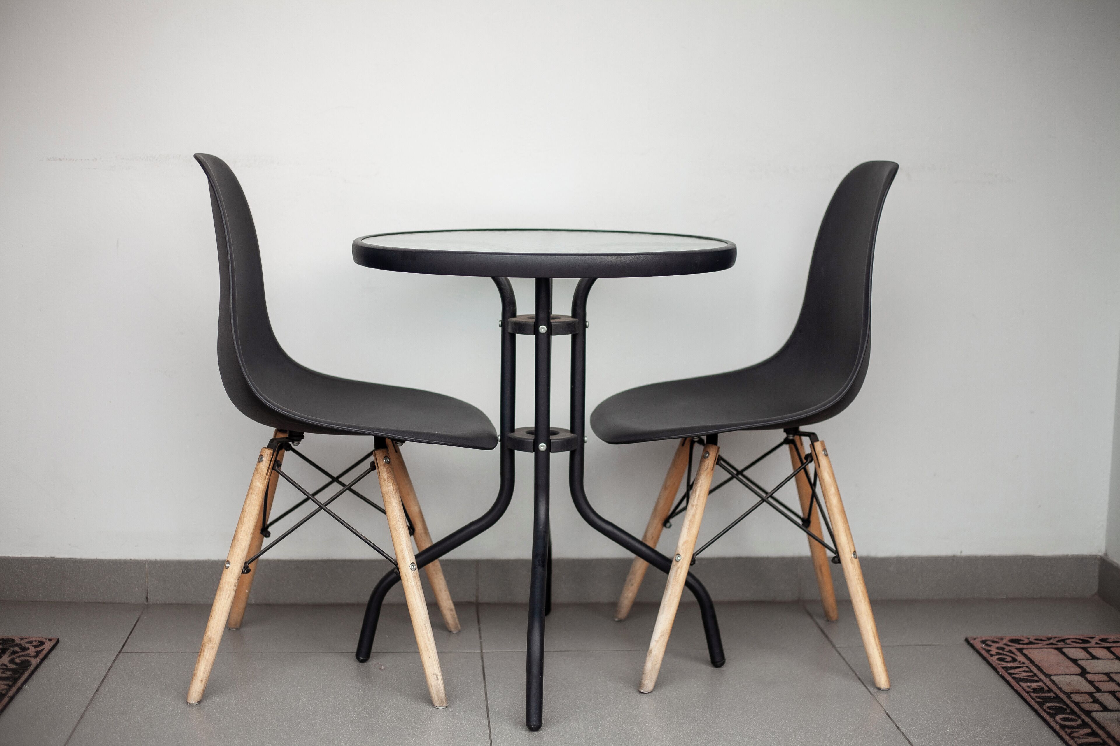 Two black chairs with wooden legs and a black metal table.