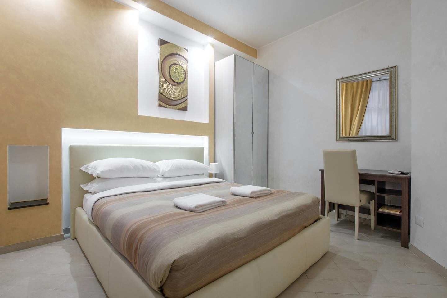 Een moderne hotelkamer met een groot bed, een bureau en een spiegel.