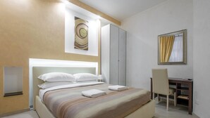 A modern hotel room with a large bed, a desk, and a mirror. - Gold Vatican Apartment (Rome)