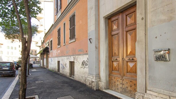 A narrow street with a tree, a parked car, and a building with a large wooden door and a mailbox. - Gold Vatican Apartment (Rome)