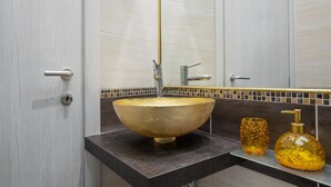 A bathroom with a large gold vessel sink, a modern faucet, and a mirror above it. - Gold Vatican Apartment (Rome)